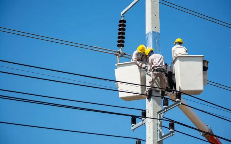 Electricians wearing safety gear work on power lines in Nakhon Ratchasima, Thailand.