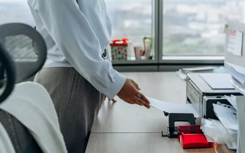 Business professional printing a document in an office environment.