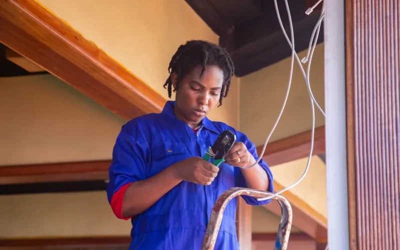 Professional electrician working on wiring in an indoor setting, demonstrating skill and concentration.