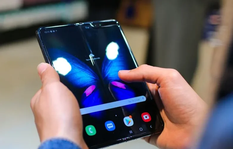 Close-up of hands holding a foldable smartphone showing a butterfly on the screen.