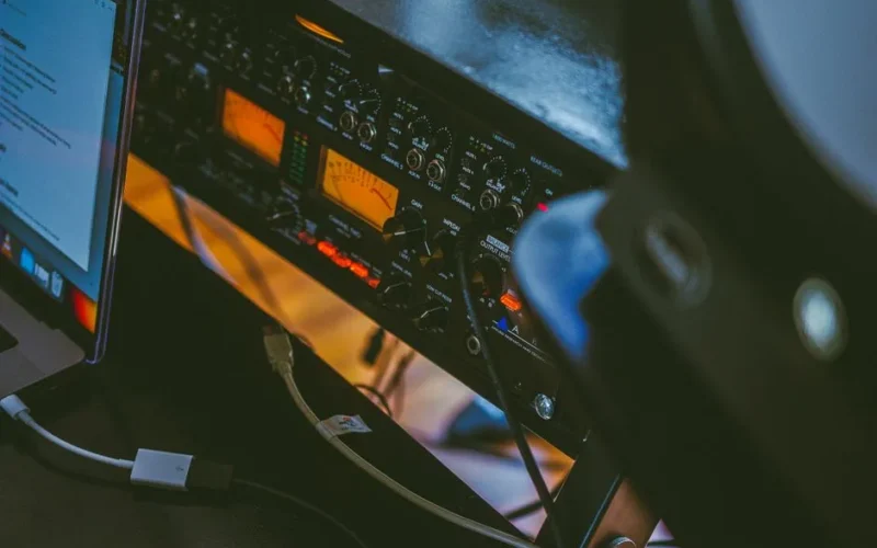 Close-up of a professional audio setup with an amplifier and a connected laptop in a workspace.