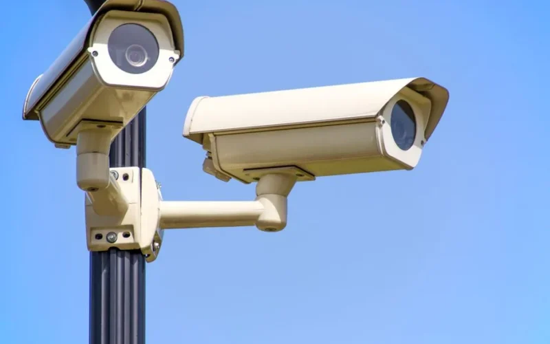Outdoor security cameras mounted on a pole against a clear blue sky, ensuring vigilant surveillance.