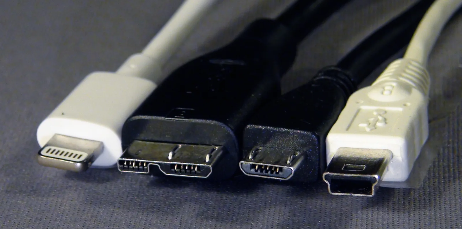 Od lewej wtyk Apple Lightning oraz wtyki USB 3 Micro-B, USB 2 Micro-B i USB Mini-B na szarym tle