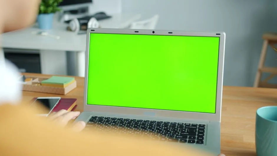 Osoba pracująca na laptopie z zielonym ekranem w nowoczesnym biurze